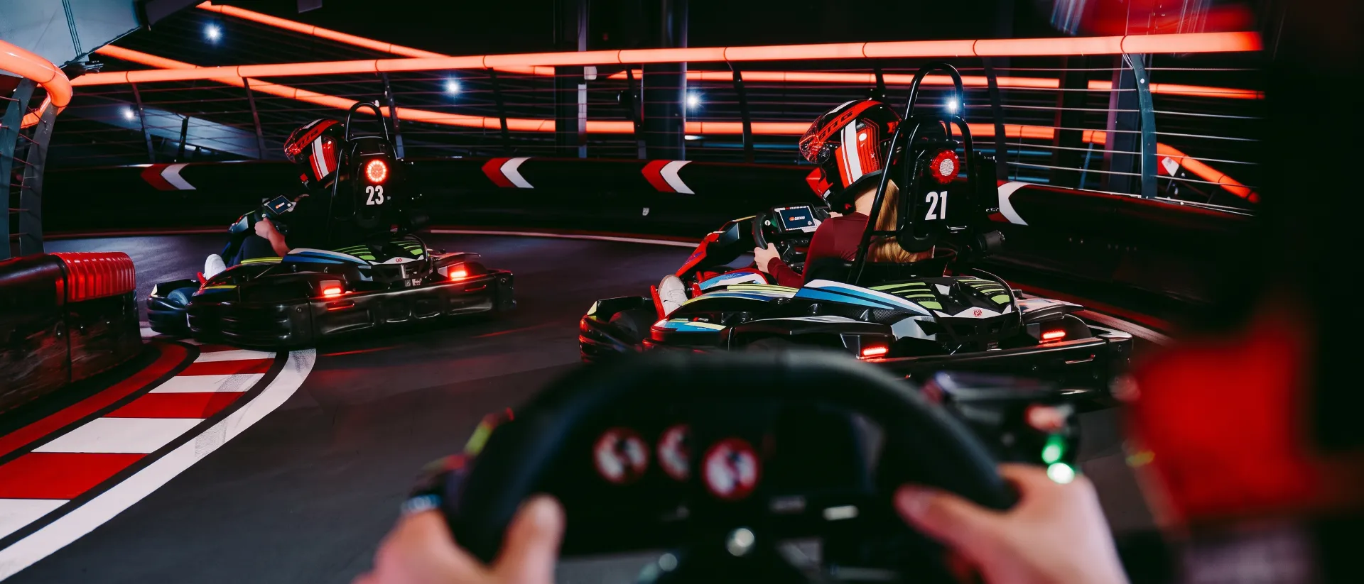 Driver’s view racing electric go-karts on a neon-lit indoor track