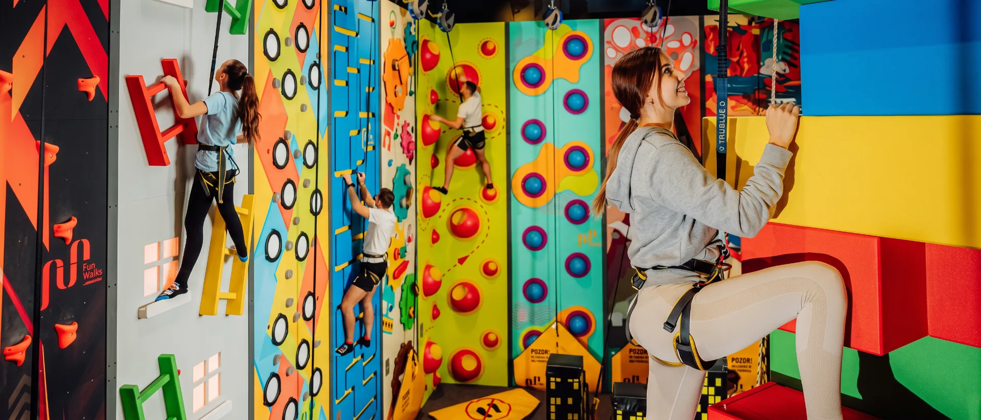 Guests climbing colorful themed walls at an indoor climbing park