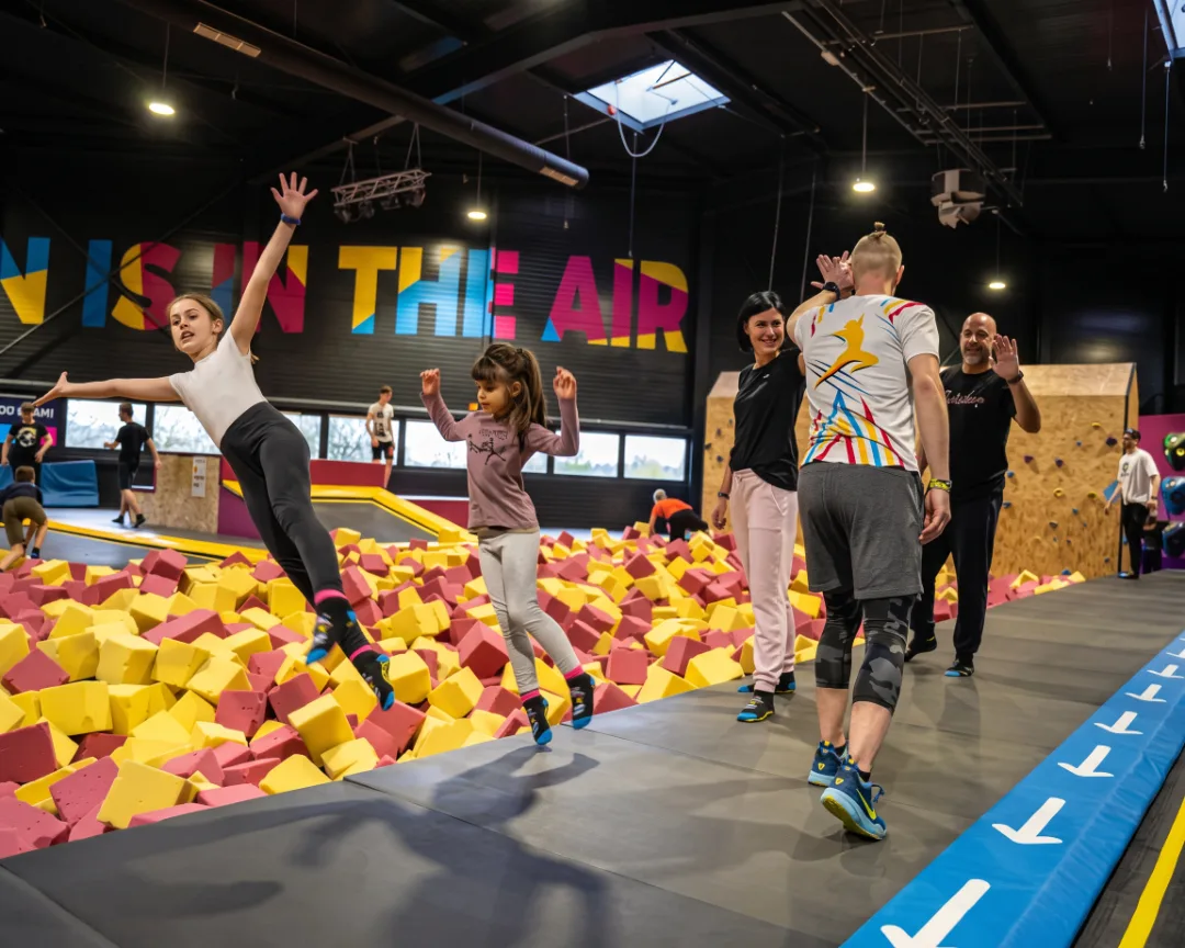 Staff greeting families beside the foam pit at a trampoline park